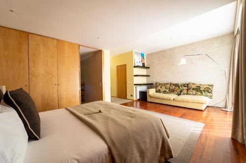 - une chambre avec un lit et un canapé dans l'établissement Casa de Silvares Fafe - Moradia Premium com piscina by House and People, à Regadas