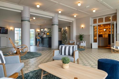 un hall d'entrée avec des canapés, des chaises et une table dans l'établissement Hôtel Morgat Le Grand Hôtel De La Mer, à Crozon