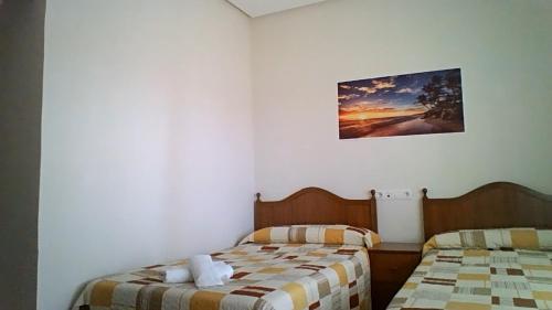 a bedroom with two beds and a picture on the wall at hostal restaurante galicia in Villardefrades