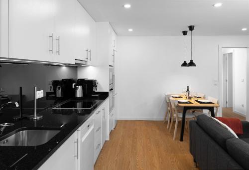 a kitchen with black counters and a table and a couch at East River - T4 junto ao Altice Forum - Braga in Braga