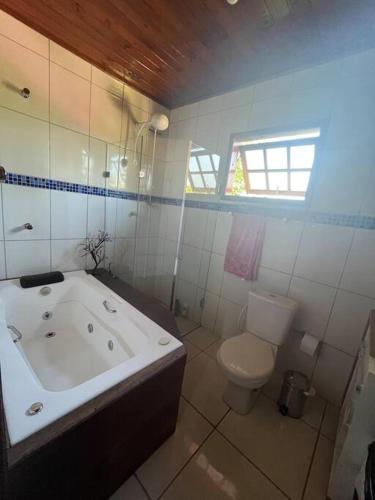 a white bathroom with a tub and a toilet at Bem vindos a Vila da Paz Itaara in Itaara
