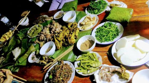 einen Tisch mit Teller mit Lebensmitteln mit Essstäbchen und Gemüse in der Unterkunft Pù Luông Jungle Homestay in Pu Luong