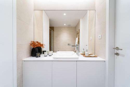 La salle de bains blanche est pourvue d'un lavabo et d'un miroir. dans l'établissement João da Ponte - T1 Altice Forum Braga by House and People, à Braga