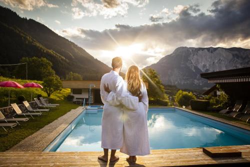 a man and woman standing next to a swimming pool at Aktiv Panoramahotel Daniel in Sautens