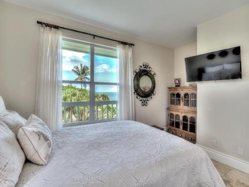 a bedroom with a bed and a large window at Sol Mar-Oceanfront Beachhouse in Captiva