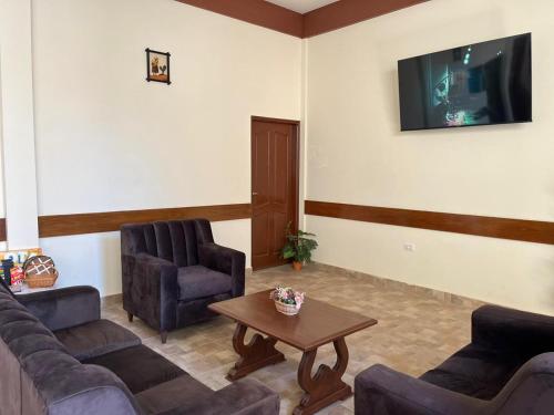 sala de estar con sofás, mesa y TV en Hostal Claure en Torotoro