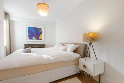 ロンドンにあるStylish Kensington Courtyard Apartmentの白いベッドルーム(ベッド1台、ランプ付)