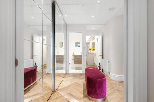 ロンドンにあるStylish Kensington Courtyard Apartmentの紫のベンチとガラスの壁が備わるリビングルーム