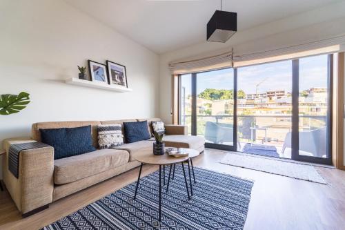 a living room with a couch and a large window at Espírito Santo - T4 apartamento familiar - Braga in Braga