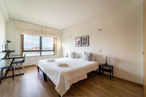 a white bedroom with a large bed and a window at Espírito Santo - T4 apartamento familiar - Braga in Braga