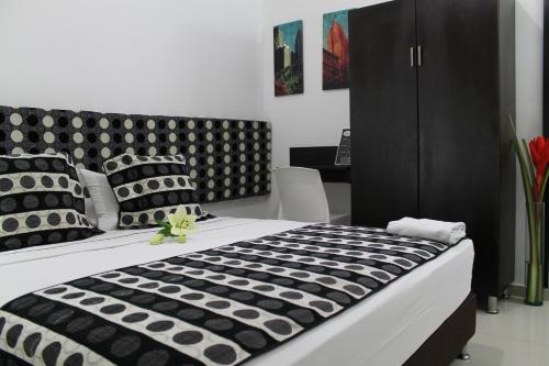 a bedroom with a large bed with black and white pillows at La Cabrera Hotel Boutique in Neiva