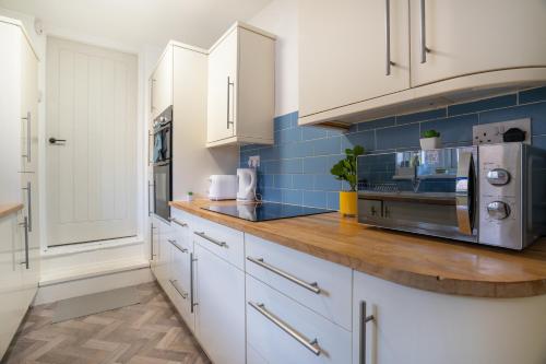 a kitchen with white cabinets and blue tiles at Cozy 3 Bed Apartment - Parking in Gateshead
