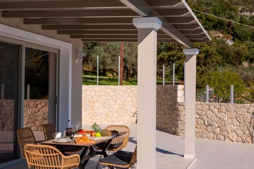 a patio with a table and chairs and a stone wall at Villa Marianna II in Nydri