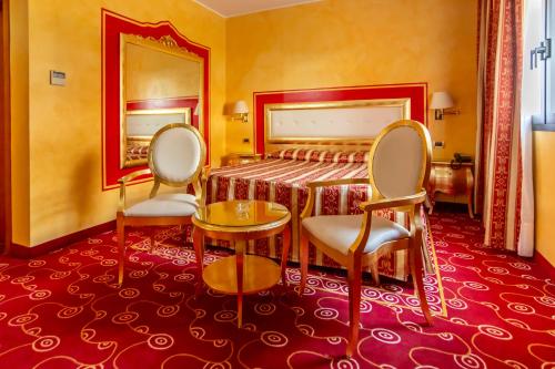 une chambre d'hôtel avec deux chaises et un lit dans l'établissement Hotel Riz B.B, à San Genesio ed Uniti