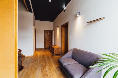 a living room with a couch and a wooden floor at Maison d'hôte Brasserie Caulier in Péruwelz