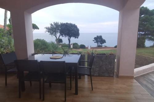 une salle à manger avec une table et des chaises et l'océan dans l'établissement Pieds dans l'eau - La Villa Crique aux tortues, à Zonza
