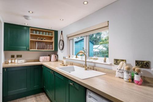 eine Küche mit grünen Schränken, einem Waschbecken und einem Fenster in der Unterkunft The Tranquil Auchterarder 3-bed Cottage in Auchterarder