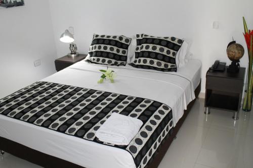 a large bed with black and white sheets and pillows at La Cabrera Hotel Boutique in Neiva