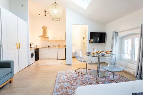 a living room with a glass table and a kitchen at Charmant Studio au cœur des Marais Salants in Arles