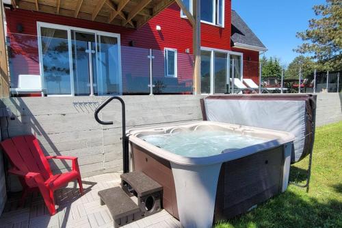 a hot tub sitting on a patio with a red chair at SkyTime Vacations in Wellington