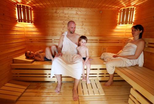 a man and woman in a sauna with a child at Aparthotel Teddy Kvilda in Kvilda