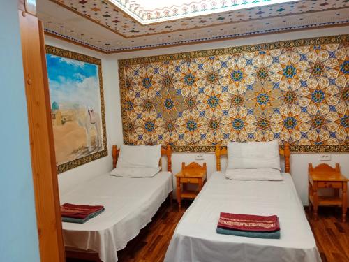 Cette chambre comprend 2 lits et un mur orné d'une fresque murale. dans l'établissement Ark & Yulduz, à Boukhara