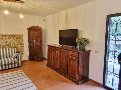 una sala de estar con TV de pantalla plana en un armario de madera en Chianti Villa Chicco, piscina privata, ampio giardino, BBQ e parcheggio, en Lucolena in Chianti