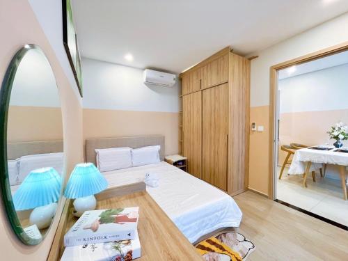 een slaapkamer met een bed en een tafel met een spiegel bij The Song QA Apartment in Vung Tau