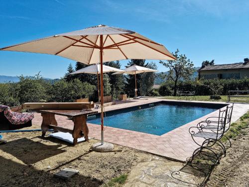 una piscina con sombrilla y mesa y un banco con mesa en Chianti Villa Chicco, piscina privata, ampio giardino, BBQ e parcheggio, en Lucolena in Chianti
