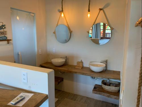 a bathroom with two sinks and two mirrors at La Paz Village Atins in Atins