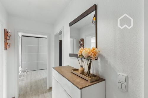 a bathroom with a mirror and a vase of flowers on a counter at Apartment close to VF Tower - 53 SQM - Fair - Kitchen in Düsseldorf