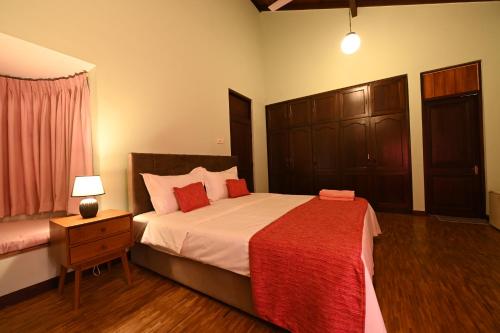 a bedroom with a large bed with a red blanket at Serene Manor in Battaramulla