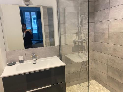 kobieta robiąca zdjęcie łazienki z umywalką i prysznicem w obiekcie La Petite Chouette, charmant et cosy T2 w mieście Dijon