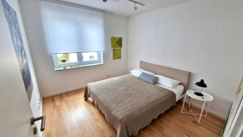 a white bedroom with a bed and a window at Residence Seeblick in Friedrichshafen