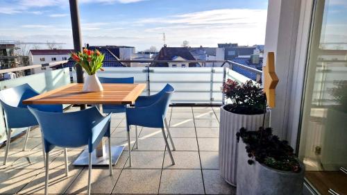 a balcony with a wooden table and blue chairs at Residence Seeblick in Friedrichshafen