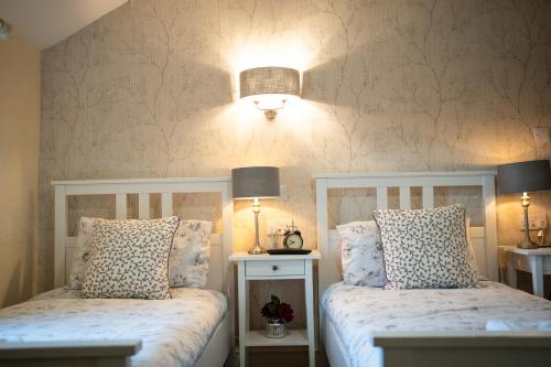 a bedroom with two white beds and a light fixture at The Shepherds Inn, Langwathby in Penrith