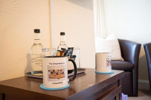 two bottles of wine and a mug on a table at The Shepherds Inn, Langwathby in Penrith