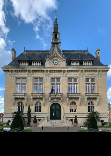 un grand bâtiment avec une tour d'horloge au sommet dans l'établissement La parisienne, à Le Raincy