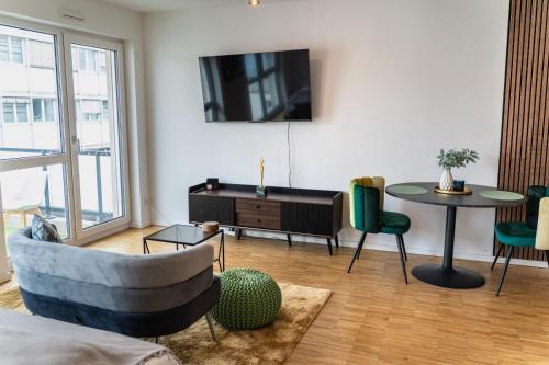 een woonkamer met een bank, een tafel en een tv bij Modernes 1 Zimmer Apartment im Zentrum Offenbachs in Offenbach