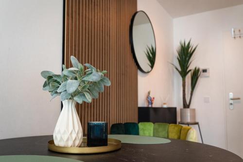 een vaas met bloemen op een tafel met een spiegel bij Modernes 1 Zimmer Apartment im Zentrum Offenbachs in Offenbach