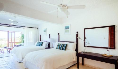 - 2 lits dans une chambre blanche avec un miroir dans l'établissement Newly Renovated 3 BR Golf Villa, à La Romana