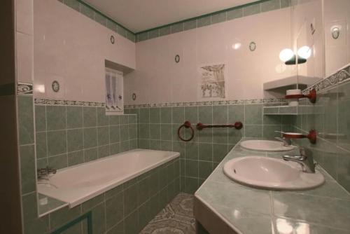 uma casa de banho com 2 lavatórios e uma banheira em Le domaine des 3 îles em Romegoux