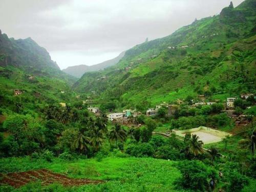 a lush green hillside with a village in a valley at Pam de Terra in Calheta de São Miguel