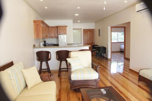a living room with a couch and chairs and a kitchen at UTILA.RENTALS in Utila