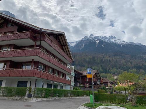 a building with red balconies next to a mountain at Seehaus Lake View 3-Bedroom Apartment in Iseltwald