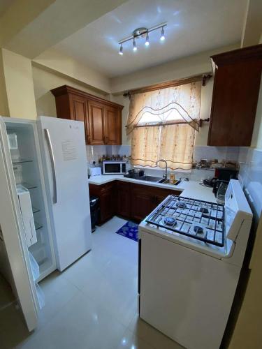 La cocina está equipada con electrodomésticos blancos y fogones. en Le Tournesol Apartments, en True Blue
