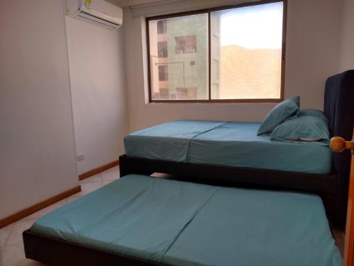 two beds in a room with a window at El Peñón frente al mar in Gaira
