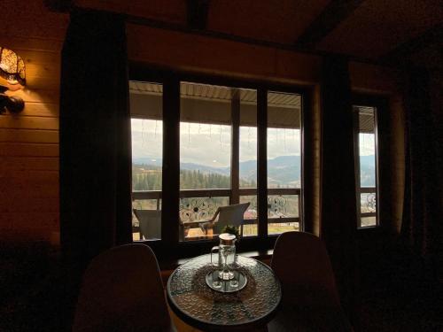a table and chairs in a room with a large window at AGORA Chalet in Slavske