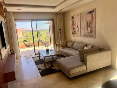 una sala de estar con un sofá y una mesa en New appart, pool and golf view, en Marrakech