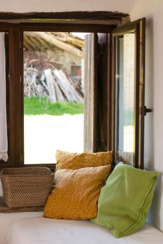 a couch with pillows sitting in front of a window at O Chardinet d'a Formiga in Aínsa